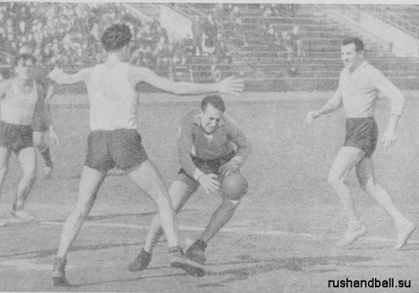 1955 ручной мяч Встреча команд Риги и Львова. Нападающий рижан, ведя мяч ударами о землю, пытается пройти между двумя защитниками команды Львова.